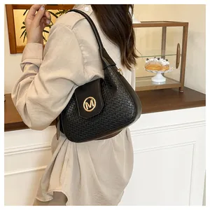Detail of black woven texture shoulder bag featuring a gold M letter metal buckle