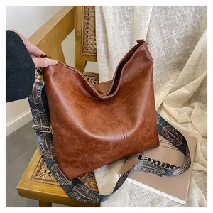 Close-up of brown textured tote bag with ethnic print strap on a vintage chair