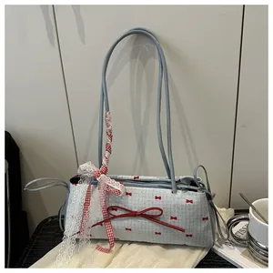 Détail du nœud en cuir rouge et de la bordure en dentelle blanche sur un sac bleu