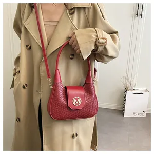 Detail view of red woven leather shoulder bag with gold M buckle and detachable strap