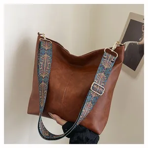 Detail of vintage brown tote bag featuring a colorful bohemian embroidered strap
