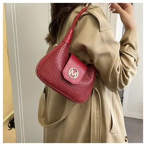 Close-up of red woven leather shoulder bag featuring a gold M logo and elegant top handle