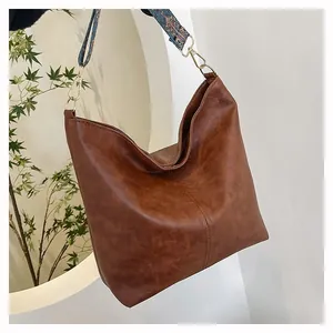 Detail of vintage brown tote bag with colorful ethnic style woven wide shoulder strap