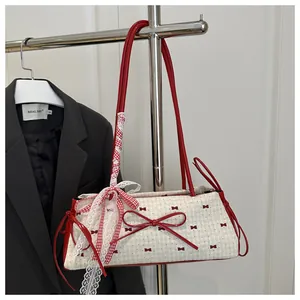 Dettaglio del motivo a fiocco rosso su borsa in tela crema con grande ciondolo in pizzo