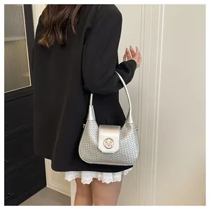 Detailed view of woven silver metallic shoulder bag with golden round M logo plaque