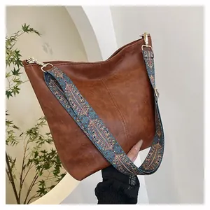 Close-up of brown faux leather tote with colorful ethnic jacquard ribbon strap