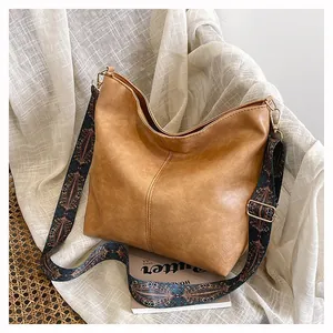 Detail of tan faux leather bucket bag with a wide ethnic jacquard patterned shoulder strap