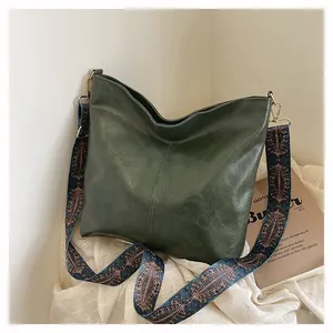Detail of dark green tote bag with ethnic style wide woven strap and pebble leather texture