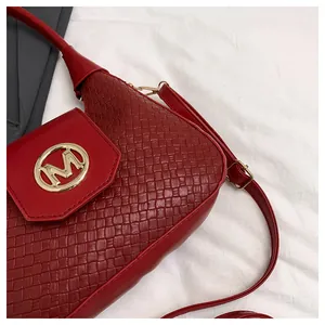 Detail shot of burgundy shoulder bag with woven texture and gold M letter metal clasp