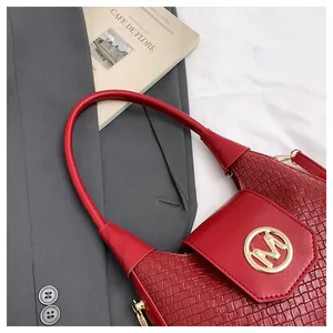 Detail of red stone texture shoulder bag with gold M-logo on a chic blazer background