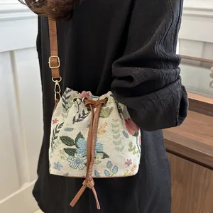 Ethnic style drawstring bucket bag with floral jacquard and brown leather strap