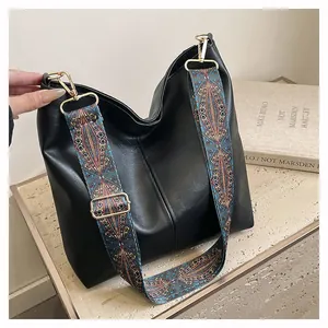 Detail of black hobo bag with bohemian colorful wide strap and gold metal hardware