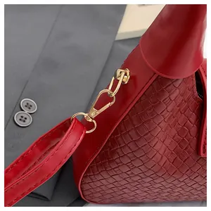 Close-up of red woven texture shoulder bag with gold-tone hardware on grey background