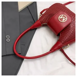 Macro detail of wine red bag showing woven texture, smooth leather and golden M logo