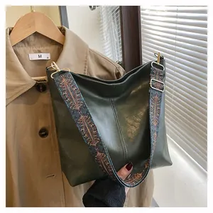 Detail of dark green leather tote bag featuring a colorful ethnic style wide shoulder strap