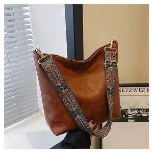Detail of vintage brown tote bag with ethnic embroidery strap and gold hardware