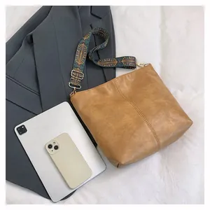 Flat lay of brown leather tote bag with bohemian strap next to a tablet and blazer
