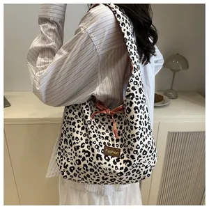 Detail of leopard print hobo bag featuring a decorative red bow and fashion leather tag