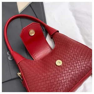 Detailed close-up of dark red woven leather bag with gold magnetic clasp on blazer