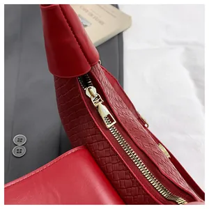 Detail of red woven leather handbag featuring premium gold zipper and textured surface