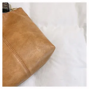 Detail of tan leather tote bag featuring vintage ethnic print strap and gold metal hook