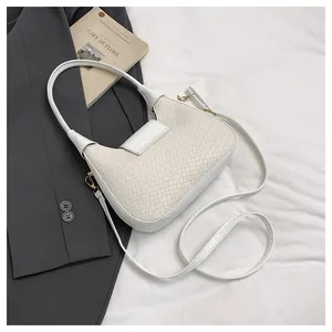 Macro detail of white woven texture and gold hardware on a minimalist crescent bag