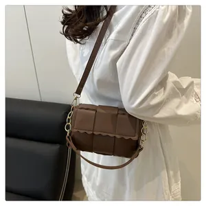 Detail of dark brown woven shoulder bag with gold chain and wavy scalloped flap edge