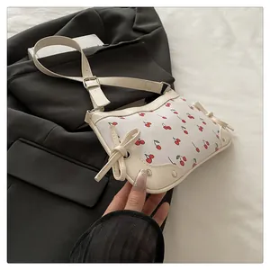 Dettaglio borsa crema con stampa ciliegie, fiocchi in pelle e rifiniture con rivetti