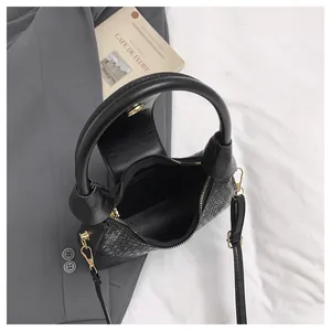 Detail of black woven shoulder bag with gold hardware and removable leather strap