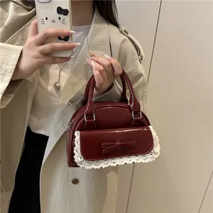 Burgundy lace bowling bag with a bow accent shown in a mirror selfie by a model