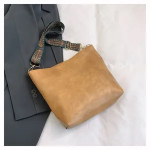 Detail of a brown PU leather tote with a retro ethnic floral patterned wide strap