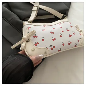 Dettaglio della borsa bianca con stampa ciliegia, fiocco decorativo e tracolla regolabile