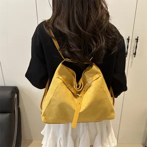 Fashionable mustard yellow suede drawstring tote bag worn as a backpack by a model