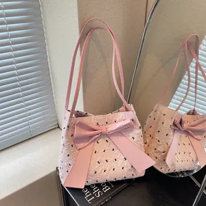 Sac à bandoulière rose avec nœuds jacquard présenté dans un reflet de miroir