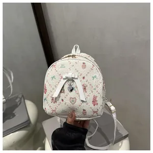 Detailed close-up of mini white backpack with floral bear prints and heart charm