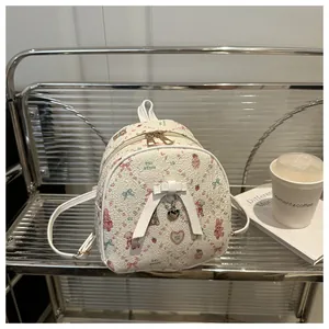 Detailed macro view of white mini backpack with pink heart patterns and golden zippers