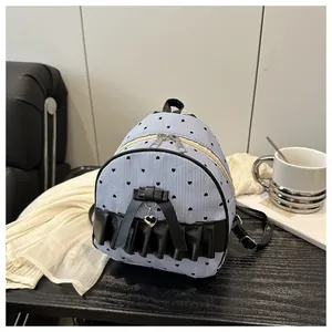 Vue détaillée du mini sac à dos en toile avec imprimé cœur, nœuds noirs et volants