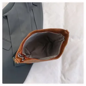Internal view of brown faux leather tote bag showing grey lining and metal zipper closure