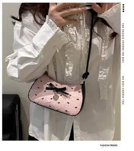 Close-up of pink crescent underarm bag with black bow and silver heart pendant detail