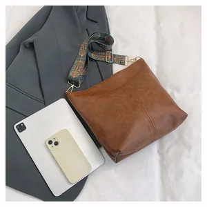 Macro shot of brown leather tote bag with colorful bohemian wide shoulder strap and gold hardware