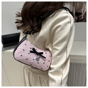 Détail du sac sous le bras en jacquard rose avec nœud noir et pendentif cœur en argent
