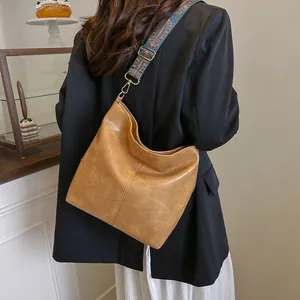 Detail of vintage brown tote bag featuring a colorful ethnic style woven shoulder strap