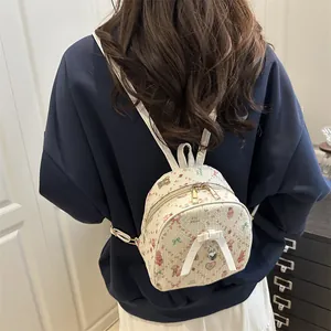 Mini cream floral backpack with strawberry bear pattern and bow shown on a person