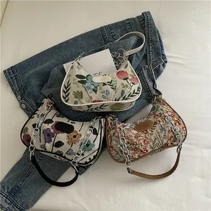 Floral embroidery crescent shoulder bag with silver chain strap on denim fabric
