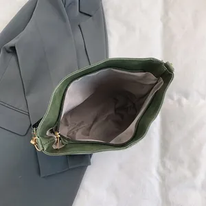 Close-up of dark green tote bag with ethnic embroidery strap and gray lining detail