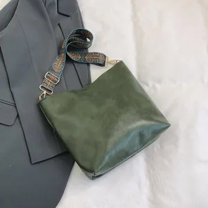 Detail of dark green matte leather tote bag with a bohemian patterned wide strap