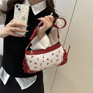 Borsa a tracolla chic con stampa ciliegia e finiture in pelle rossa indossata da modella
