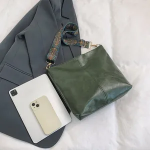Detail of green leather tote bag featuring center stitching and vintage pattern strap