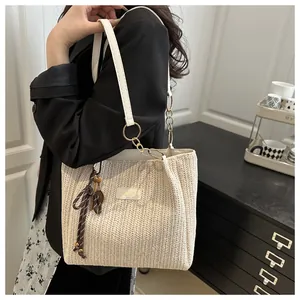 Dettaglio della borsa tote in paglia con manici in pelle bianca e fiocco decorativo in seta