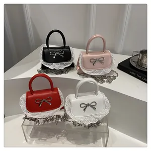 Detail van mini crossbodytassen met metalen strikken en witte kanten afwerking